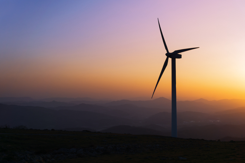 Wind turbine silhouette on mountain at sunset